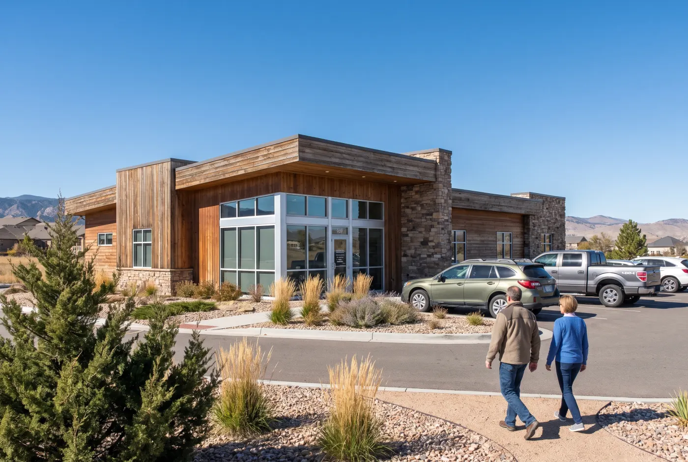 The single-story timber and stone clinic, landscaped with junipers, under a blue sky.