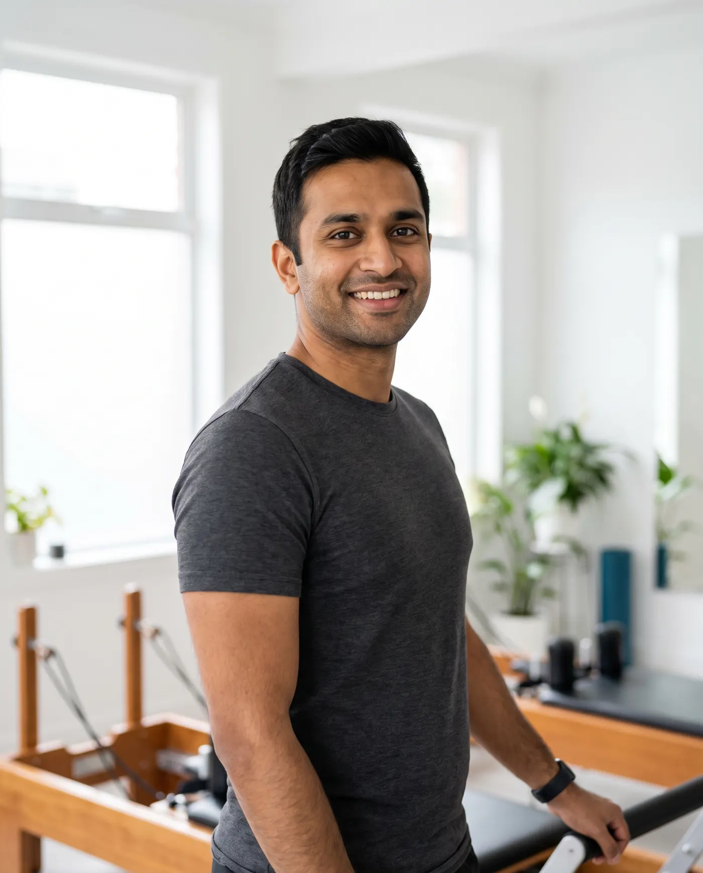 Arjun, a Pilates instructor, beside a reformer.