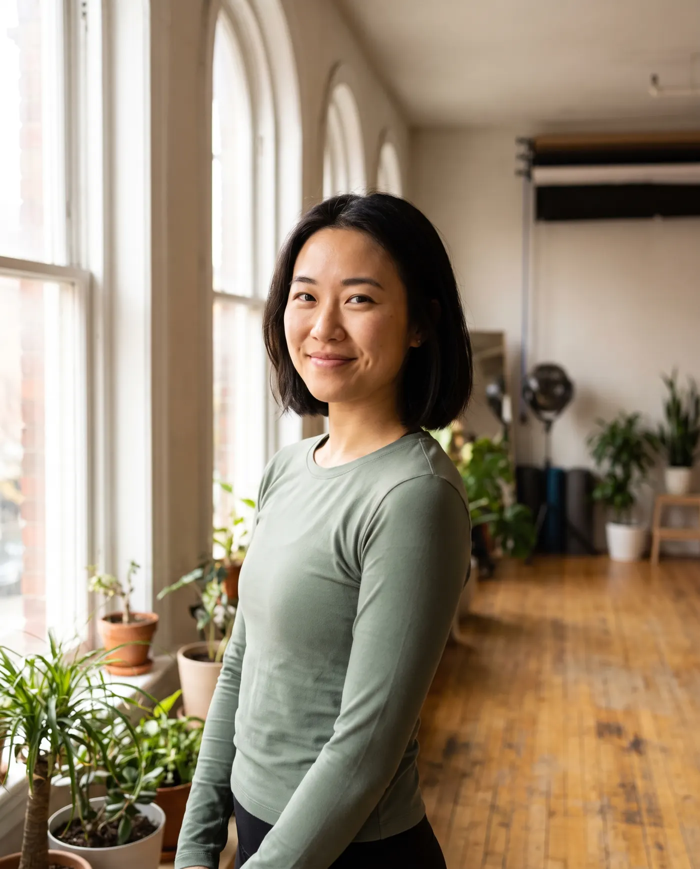 Yuna, a yoga teacher, by the tall studio windows.