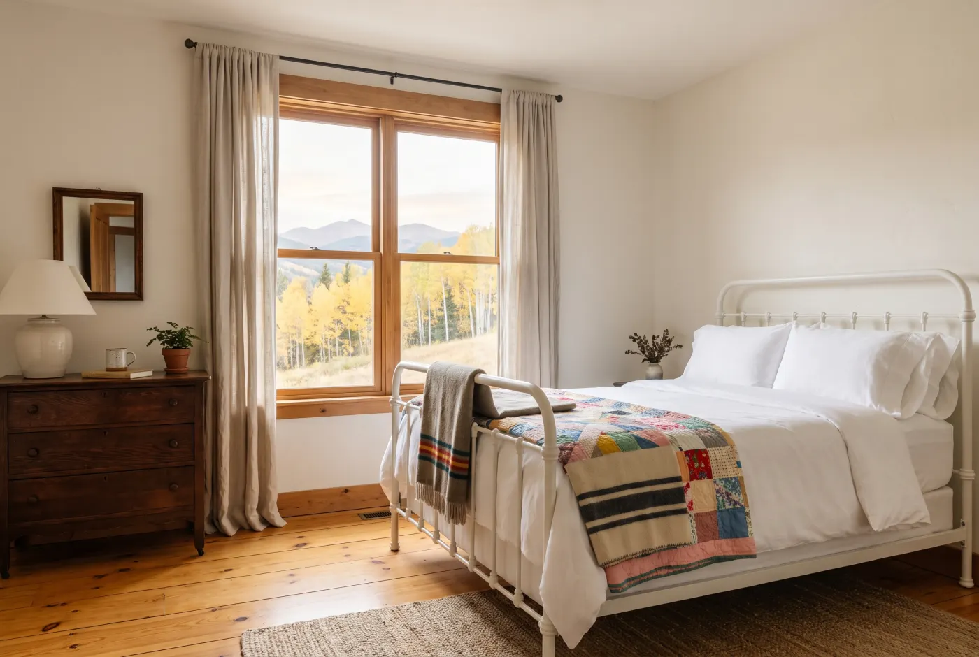The Aspen Room: an iron bed with a quilt beside a window full of golden aspens.